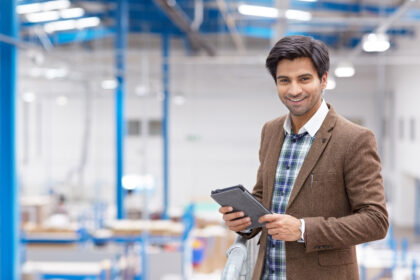 Happy young businessman with digital tablet in warehouse